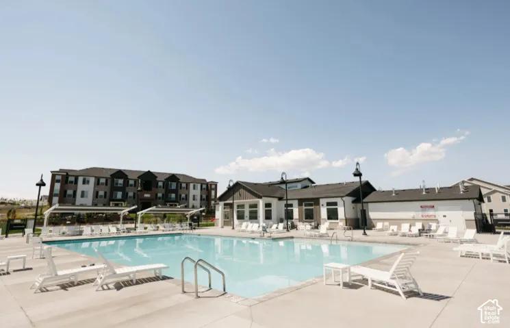 Expansive outdoor pool with integrated steps, surrounded by a concrete deck and multiple shaded lounge areas