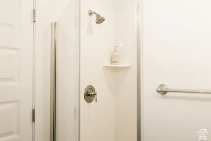 Shower with a brushed nickel showerhead, a single-handle temperature control, and a corner shelf