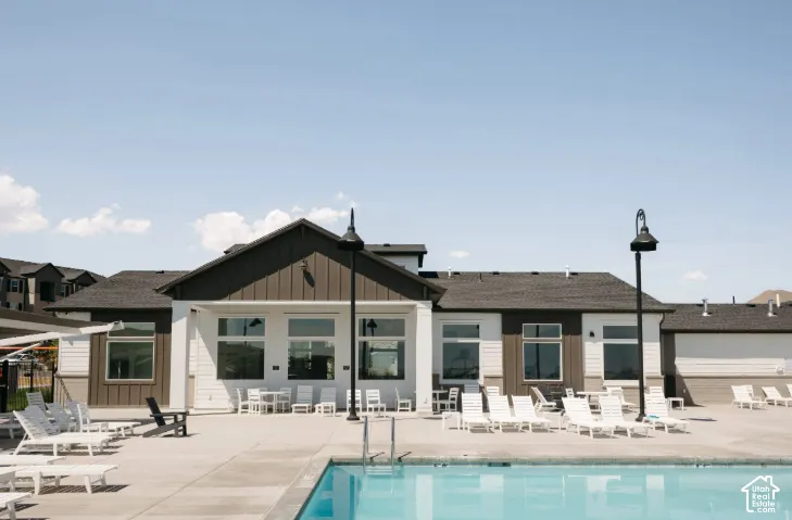 Community building with gabled roofline, concrete pool deck, and integrated swimming pool