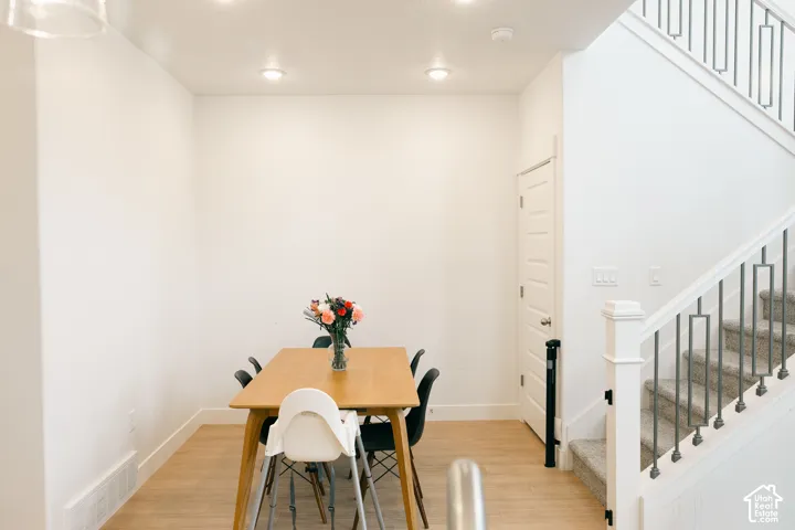 Recessed ceiling lighting illuminates the space, featuring wood-finish flooring, a paneled door, and a staircase with metal balusters