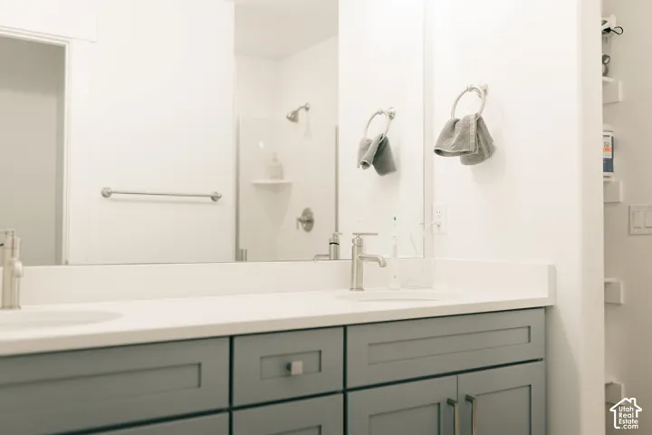 Double vanity with white countertop, undermount sinks, gray shaker-style cabinetry, and brushed nickel fixtures