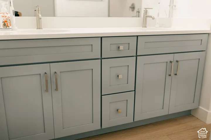 Double vanity with dual undermount sinks, single-handle faucets, and gray shaker-style cabinetry featuring varied storage options