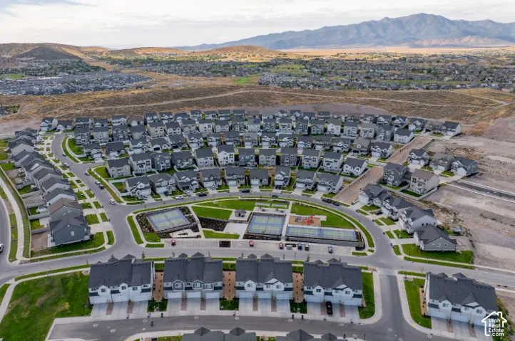 Expansive community featuring multiple residential structures, central green spaces, and dedicated recreational courts