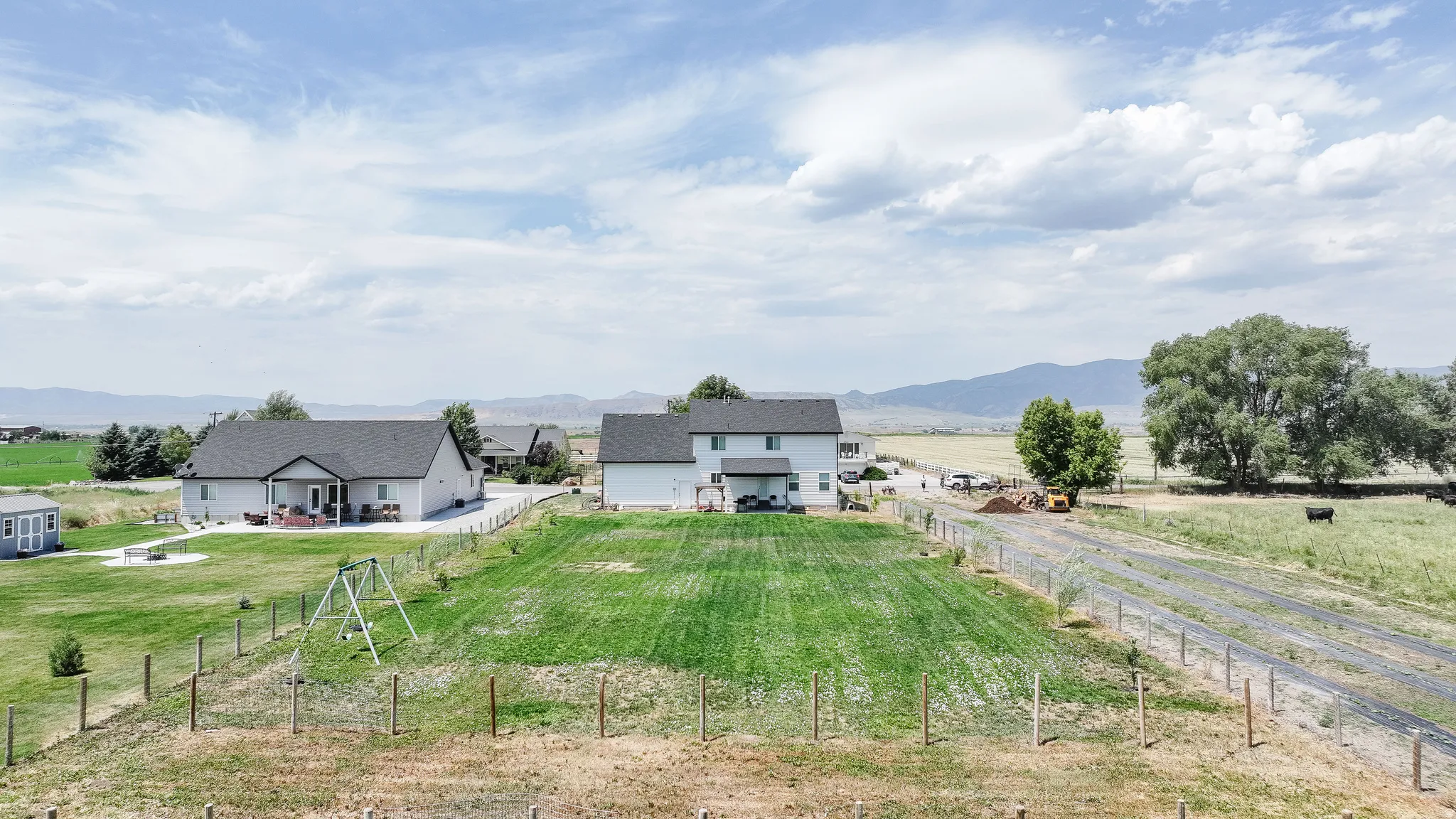 Expansive property featuring two distinct structures, a fenced perimeter, and a substantial grassy area