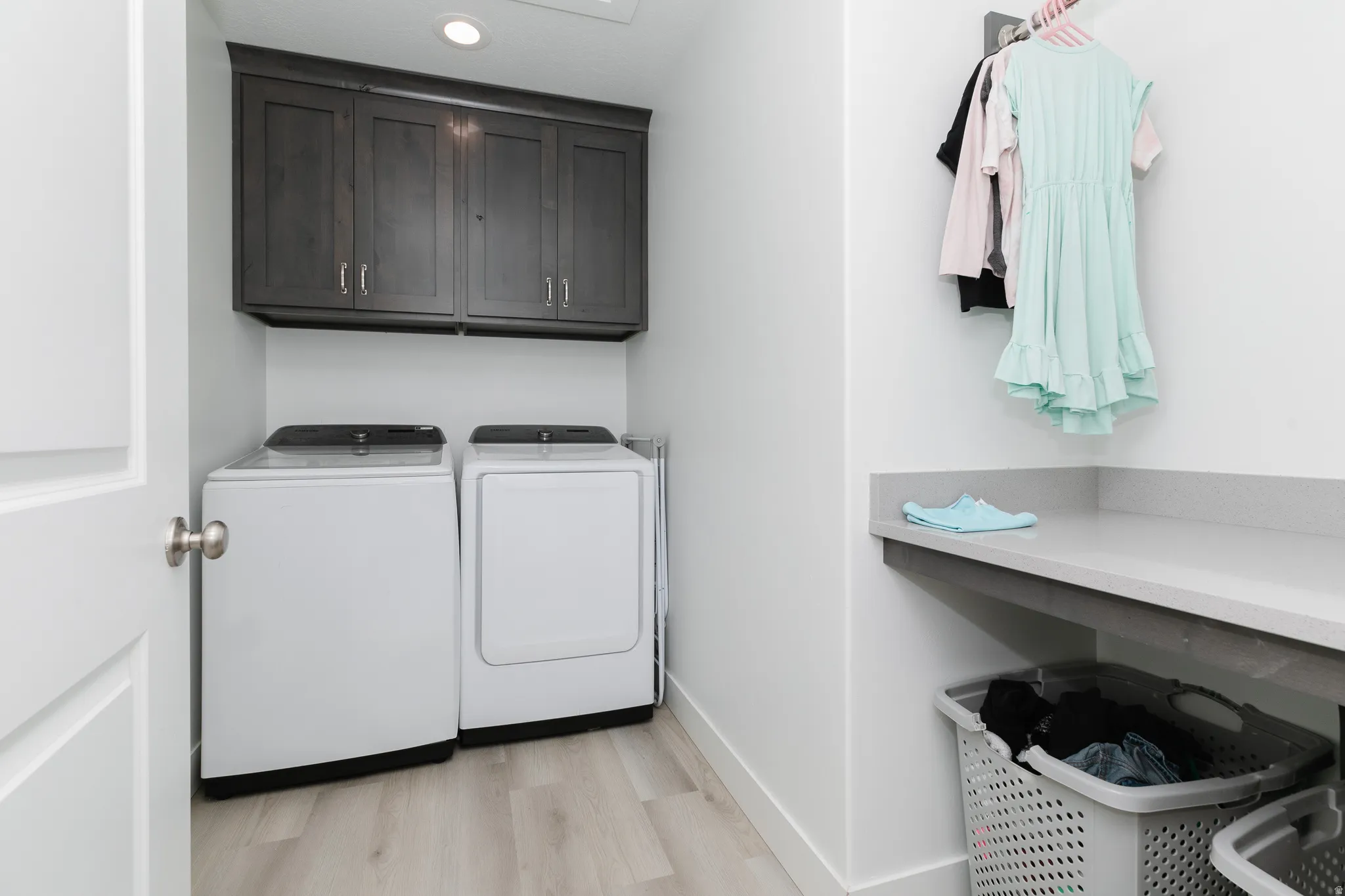 Laundry area featuring wood-finish flooring, dark-stained cabinetry, and a countertop