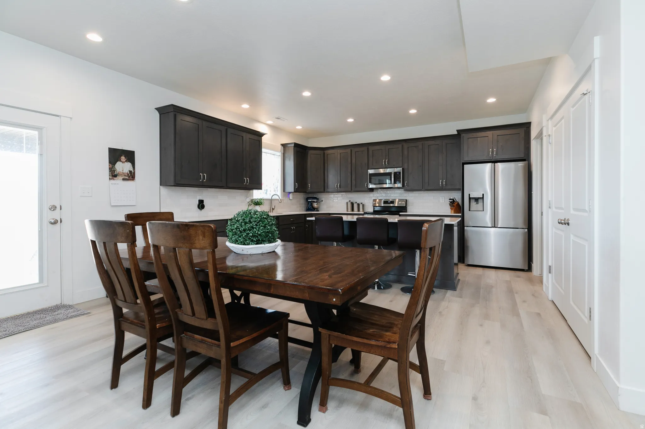 Recessed lighting throughout, dark wood-finish cabinetry, stainless steel appliances, light wood-finish flooring, and white paneled doors