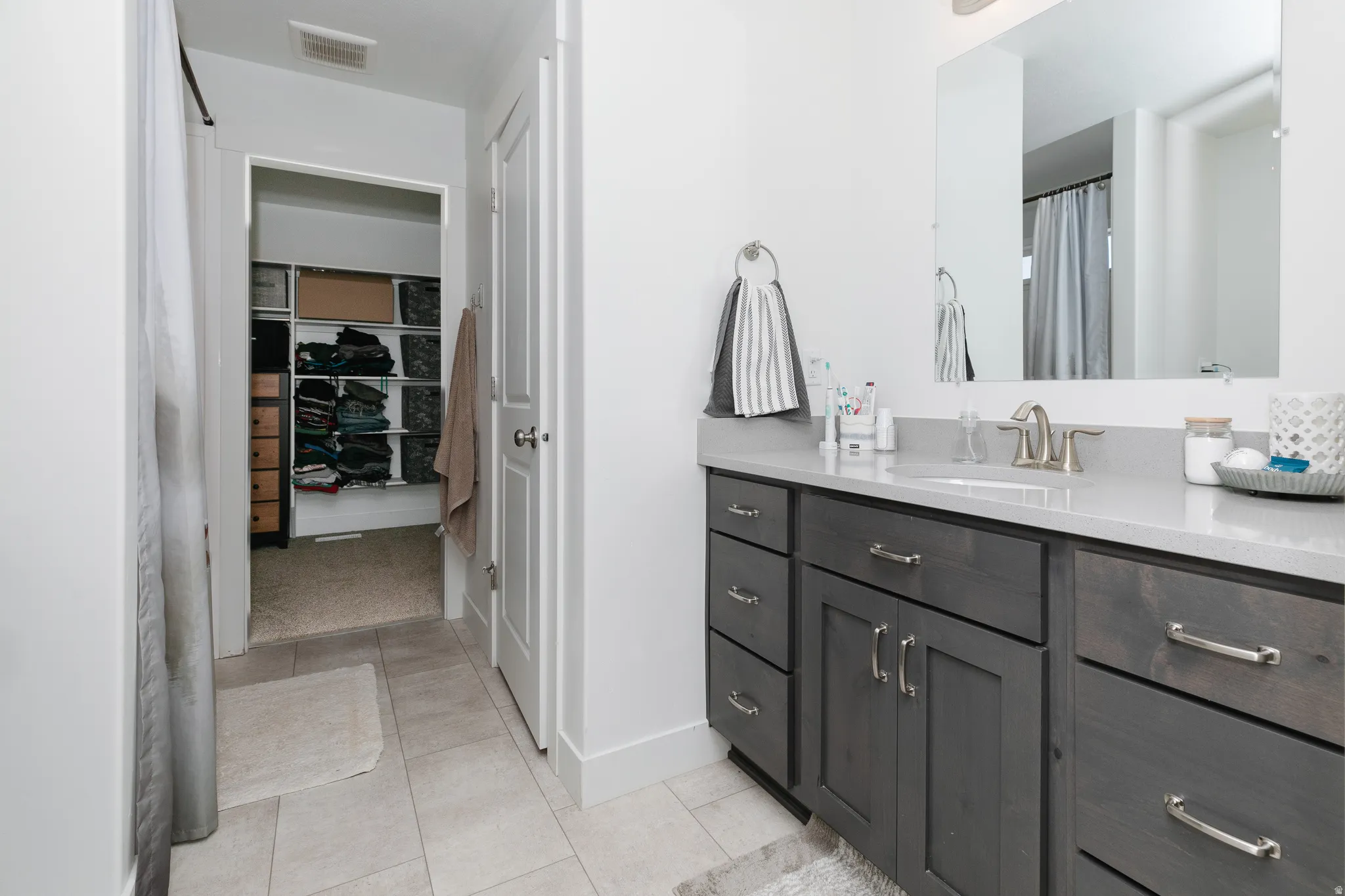 Vanity with light-toned countertop, undermount sink, and brushed nickel faucet