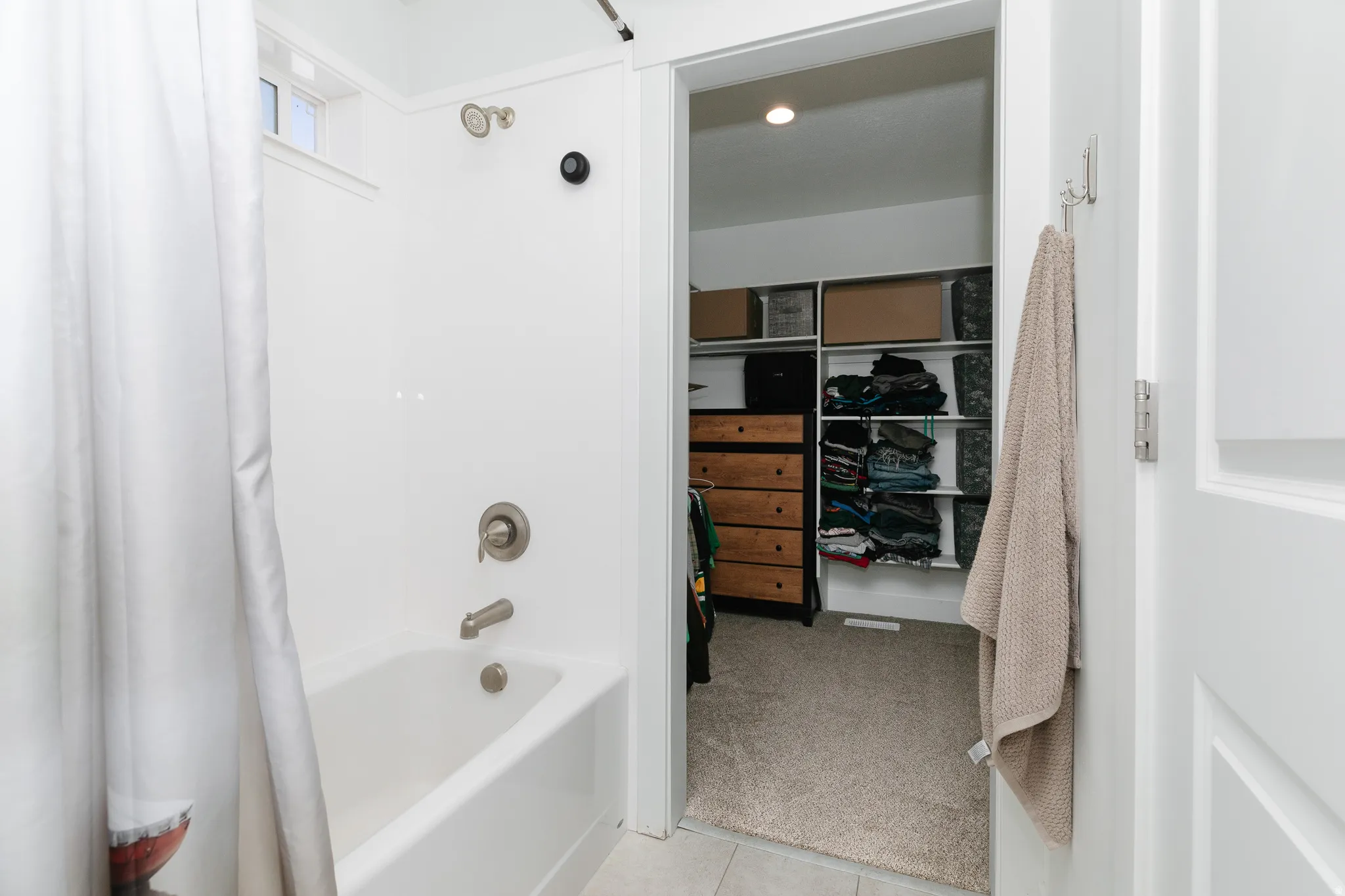 Tub and shower combination with brushed nickel fixtures and a translucent transom window