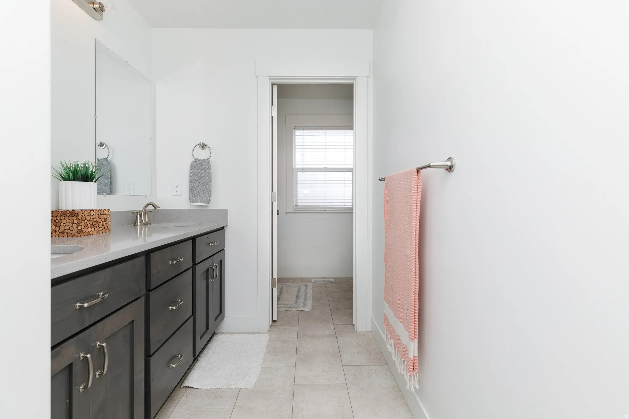 Double vanity with dark wood-finish cabinetry, light-toned countertop, and tile flooring