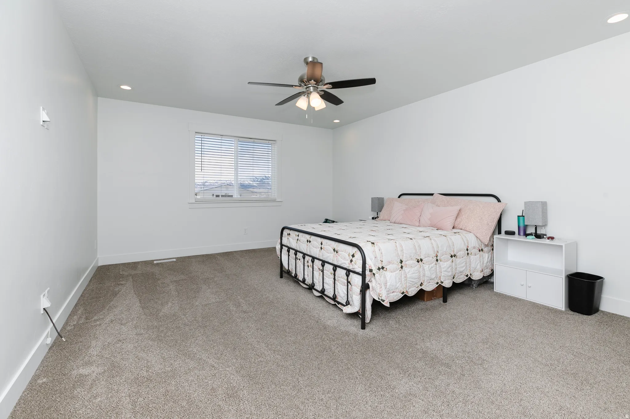 Recessed lighting, ceiling fan with integrated light, horizontal blinds, and neutral carpeting