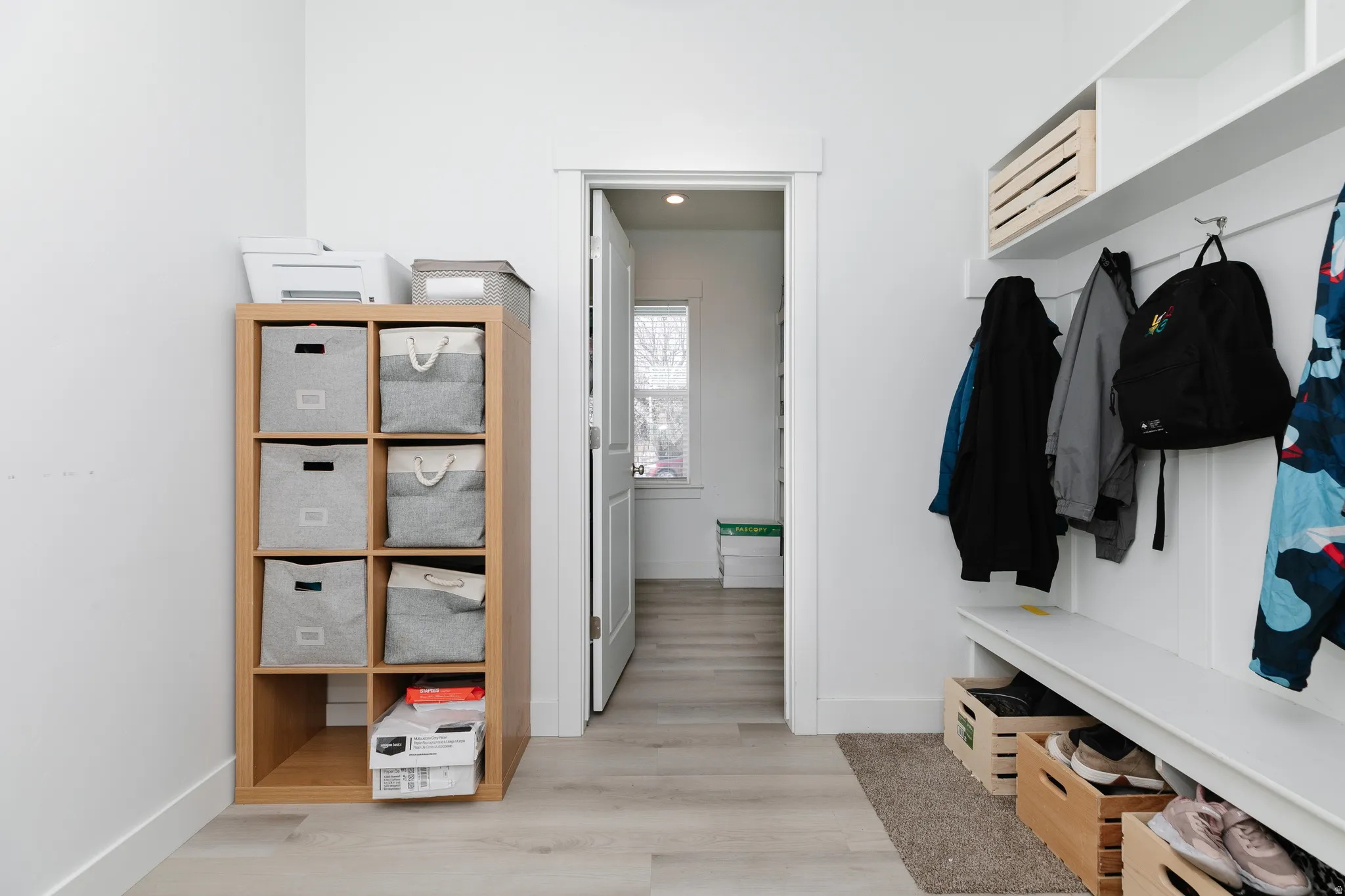 Built-in white storage bench with upper shelving and coat hooks