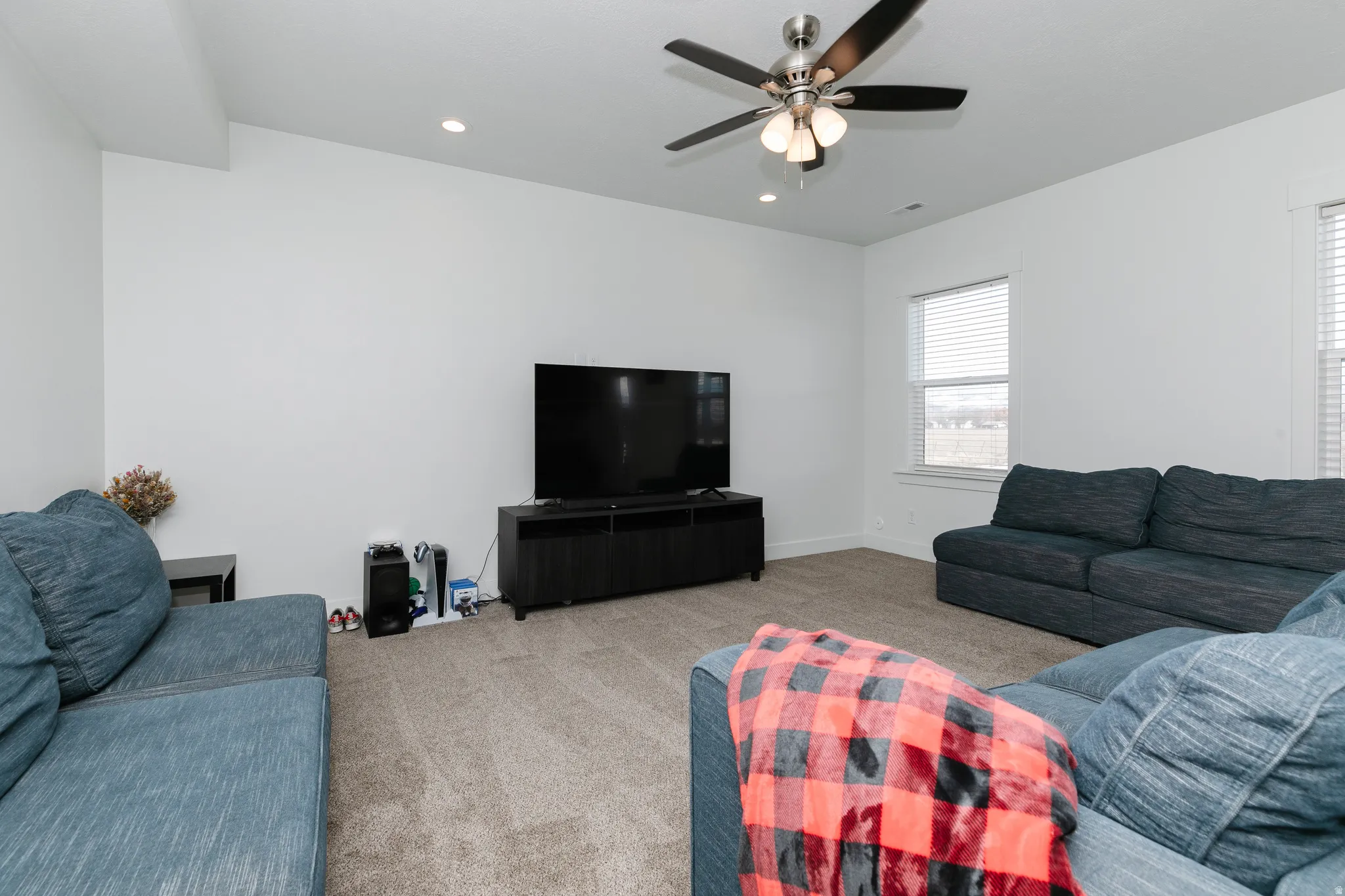 Carpeted living space with a ceiling fan, recessed lighting, and multiple windows