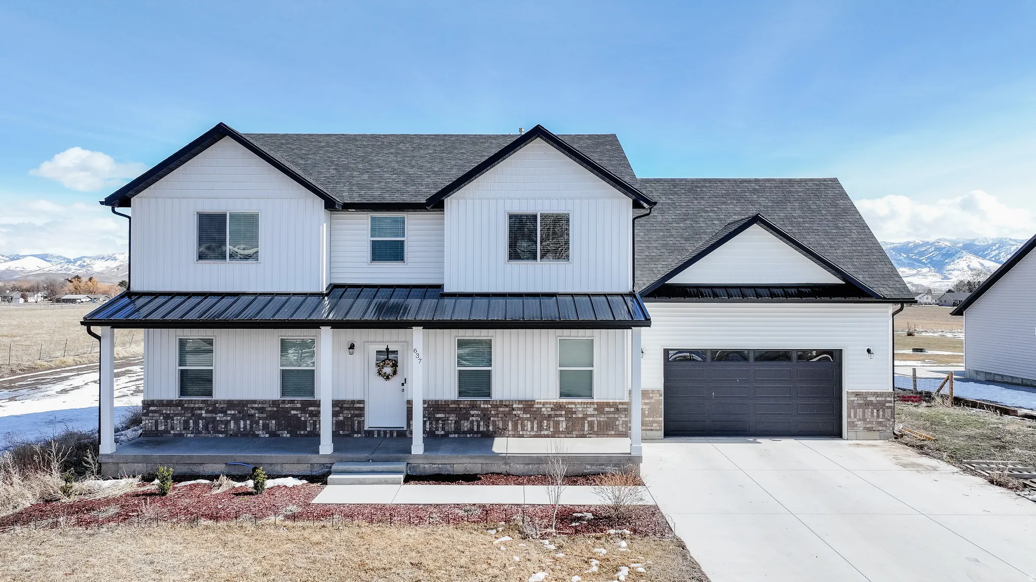 Two-story residence featuring white siding, a dark asphalt shingle roof, and a covered front porch with white columns