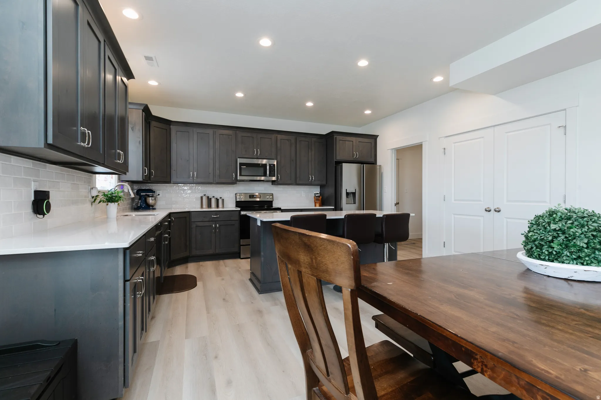Kitchen featuring dark wood-finish cabinetry, light countertops, subway tile backsplash, and stainless steel appliances