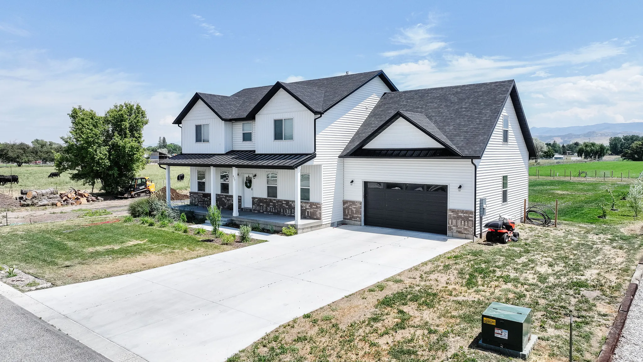 Contemporary farmhouse-style residence with white siding, dark gabled roofing, and a prominent attached garage