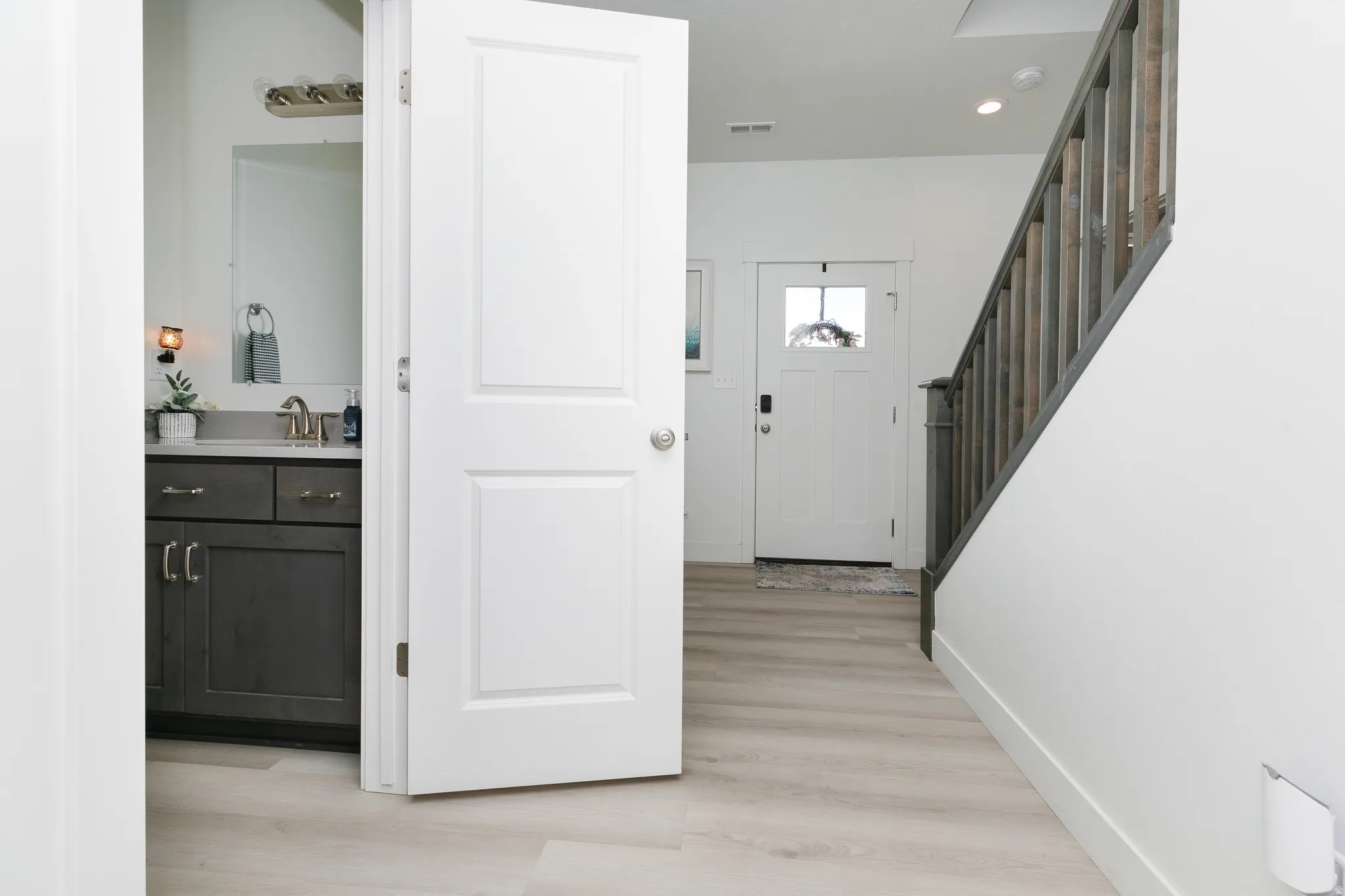 Entryway featuring wood-finish flooring, a white paneled door with glass insert, and a staircase with a wood railing