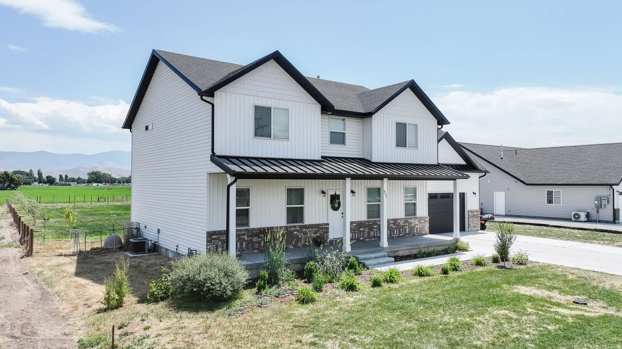 Two-story residence featuring a covered front porch, attached single-car garage, and a separate detached garage structure