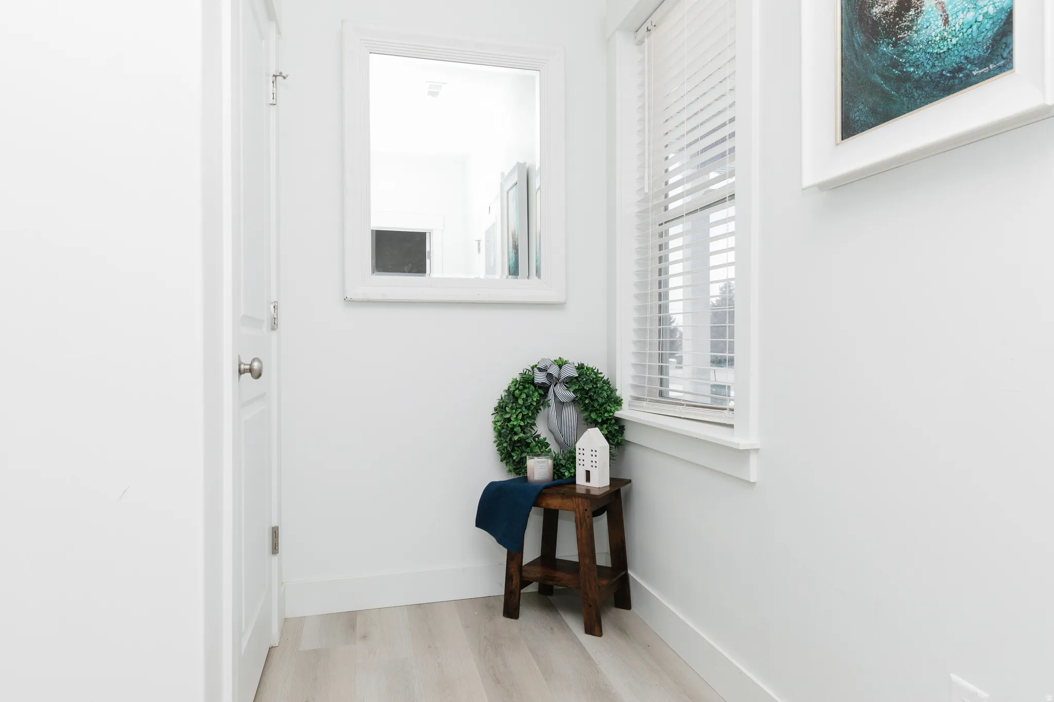 Light wood-finish flooring, white walls, and a window with blinds