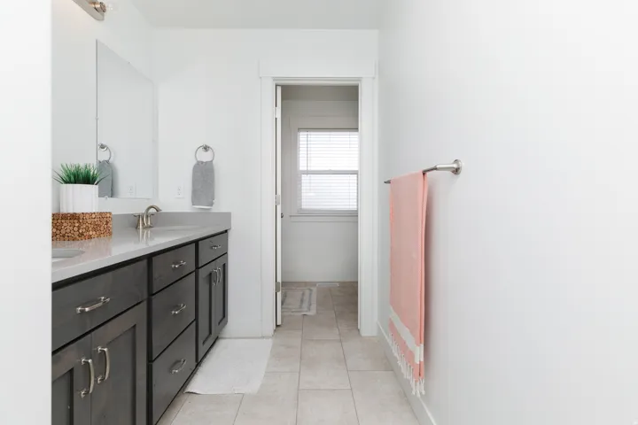 Double vanity with dark wood-finish cabinetry, light-toned countertop, and tile flooring