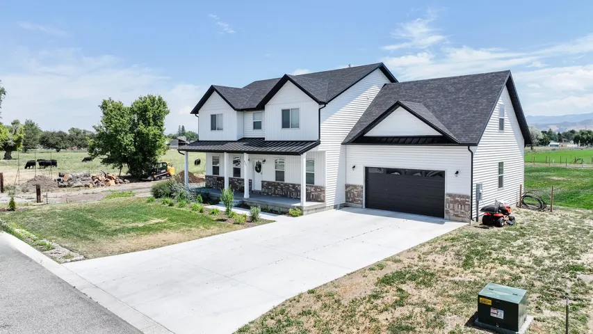 Contemporary two-story exterior with white siding, dark gabled roof, stone accents, attached garage with dark door, and concrete driveway