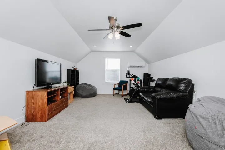 Carpeted attic space featuring sloped ceilings, recessed lighting, and a ceiling fan