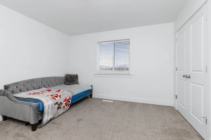 Light-colored carpeting, white wall finishes, a window with horizontal blinds, and a white paneled door with a silver-tone knob