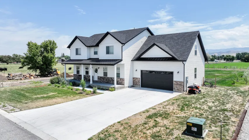 Contemporary farmhouse-style residence with white siding, dark gabled roofing, and a prominent attached garage