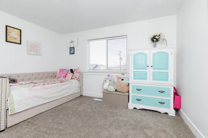 Room featuring neutral wall paint, white trim, a single window with blinds, and textured carpet