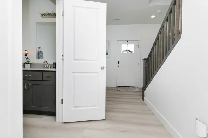 Entryway featuring wood-finish flooring, a white paneled door with glass insert, and a staircase with a wood railing