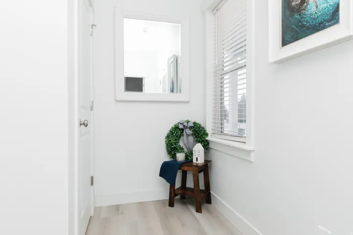 Light wood-finish flooring, white walls, and a window with blinds