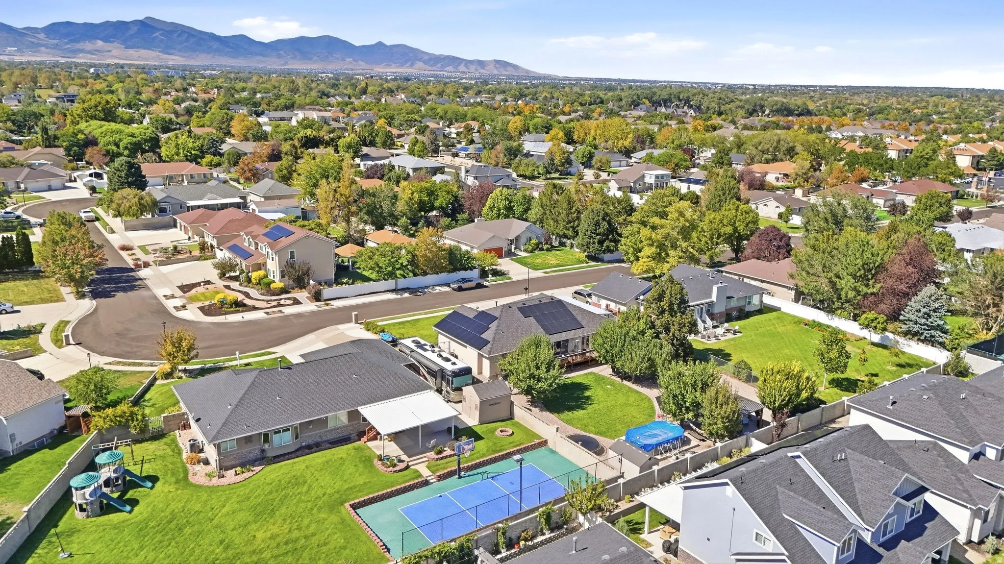 Expansive lot featuring a sports court, mature trees, and a covered patio