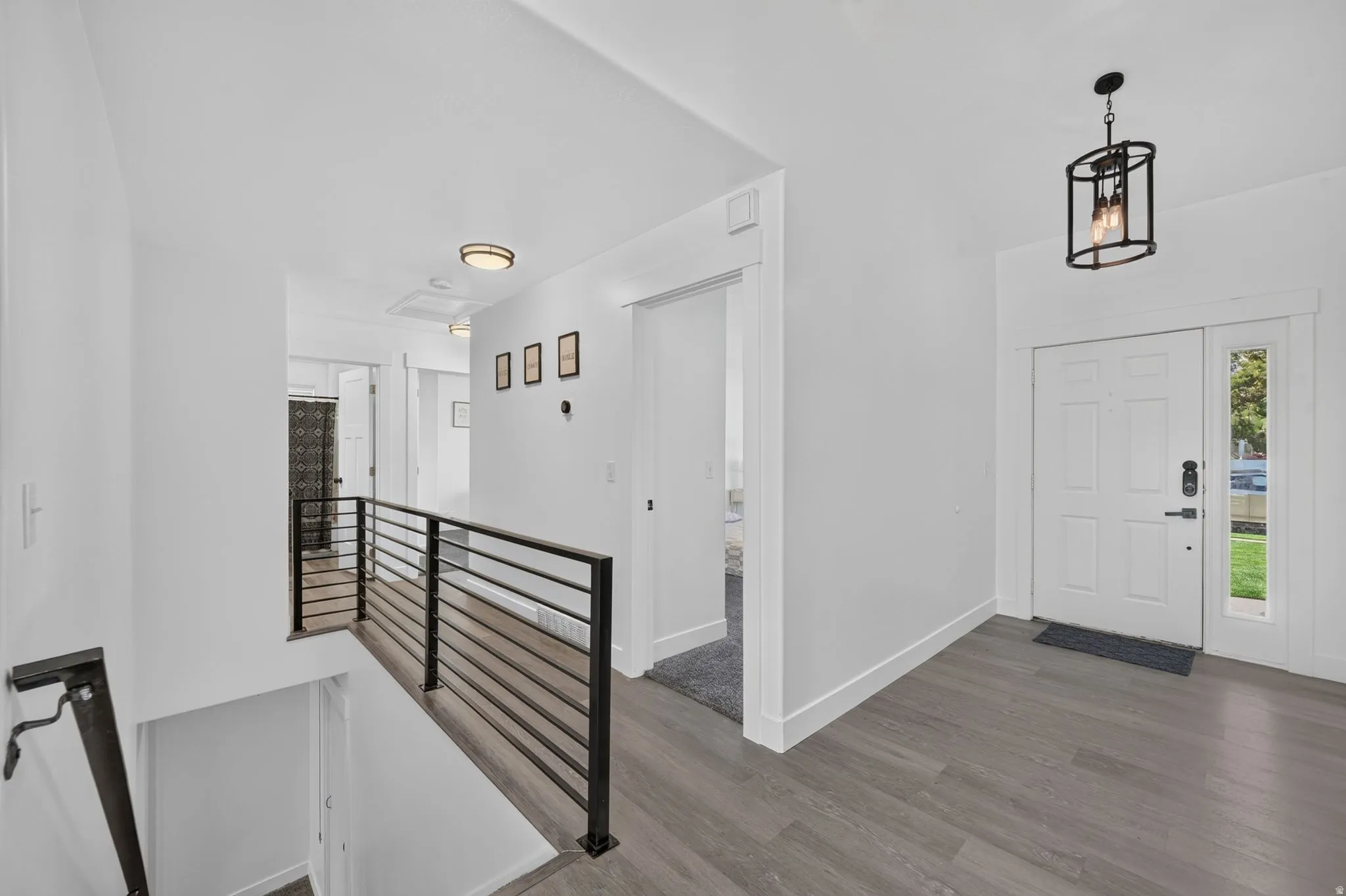 Entryway featuring wood-finish flooring, a white paneled door with a sidelight, and a black metal-framed pendant light