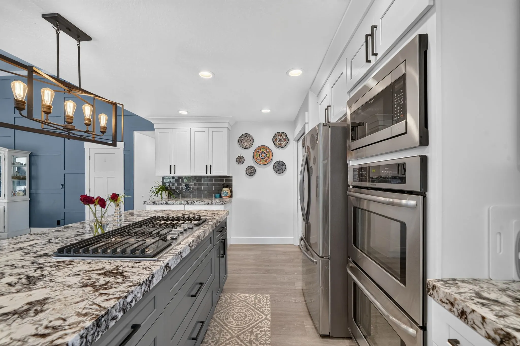 Expansive kitchen island with an integrated gas cooktop, stone countertop, and pendant lighting
