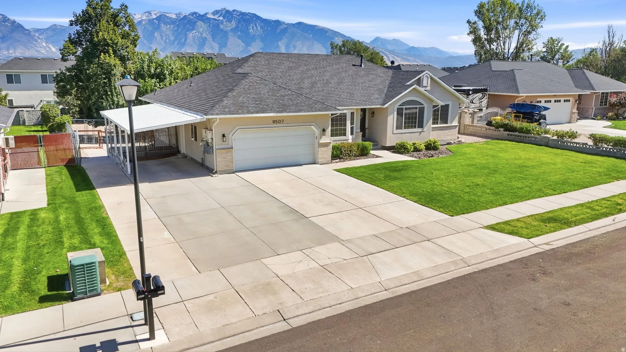 Single-story property with a two-car garage, expansive concrete driveway, and a covered carport