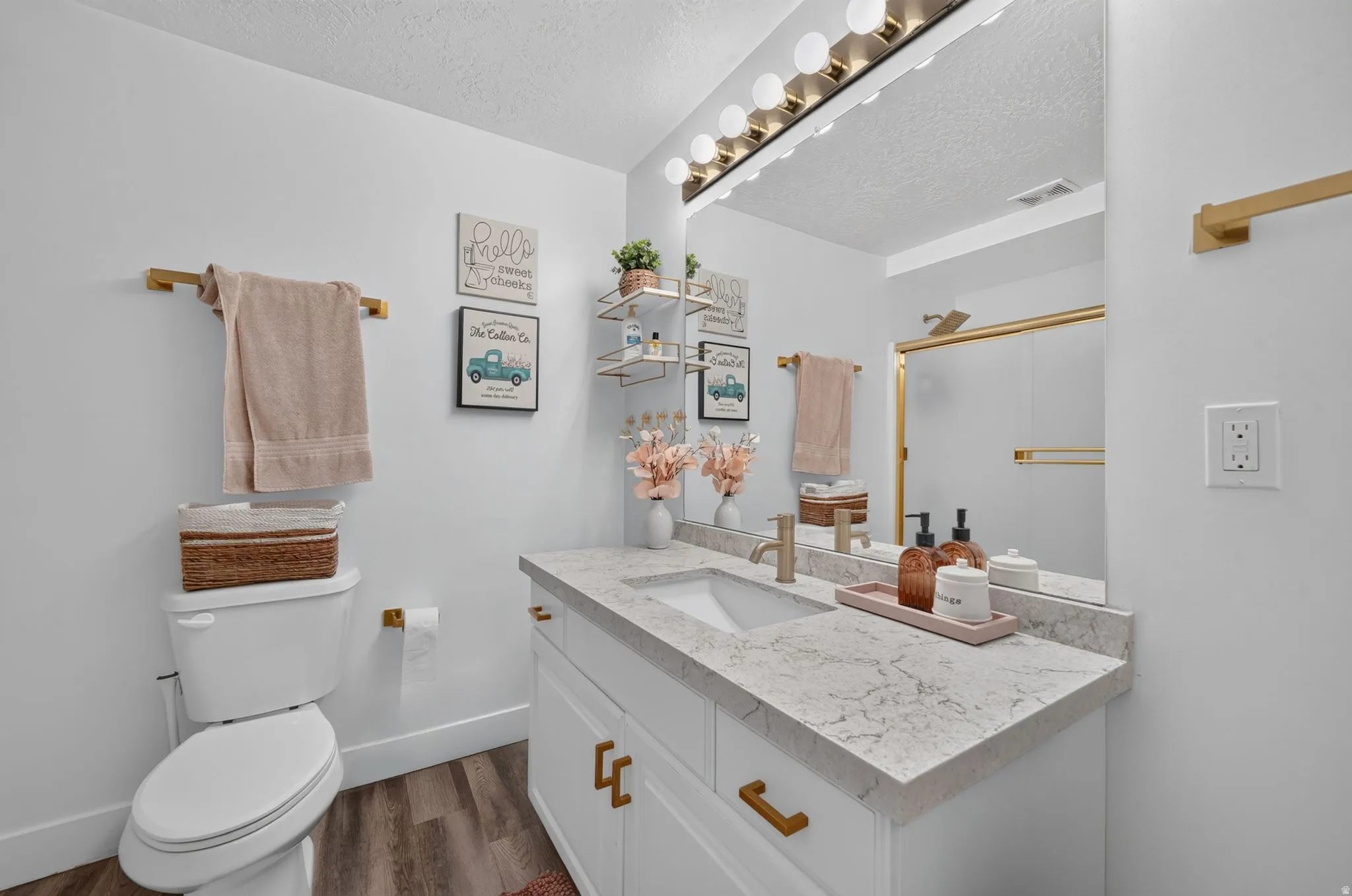 White vanity with brass hardware, undermount sink, and light-toned countertop