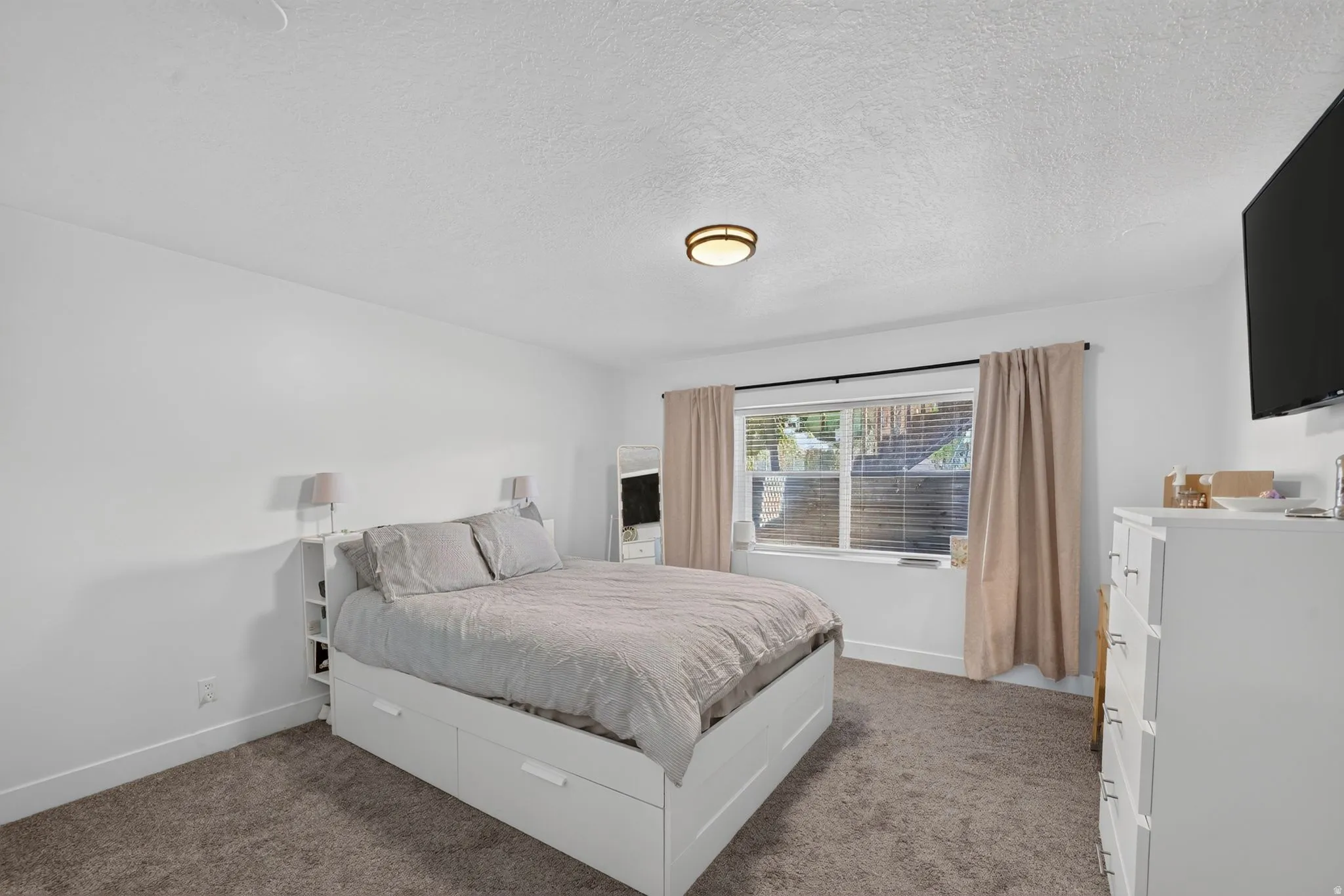 White painted walls, carpeted flooring, a flush-mount ceiling light fixture, and a window with blinds