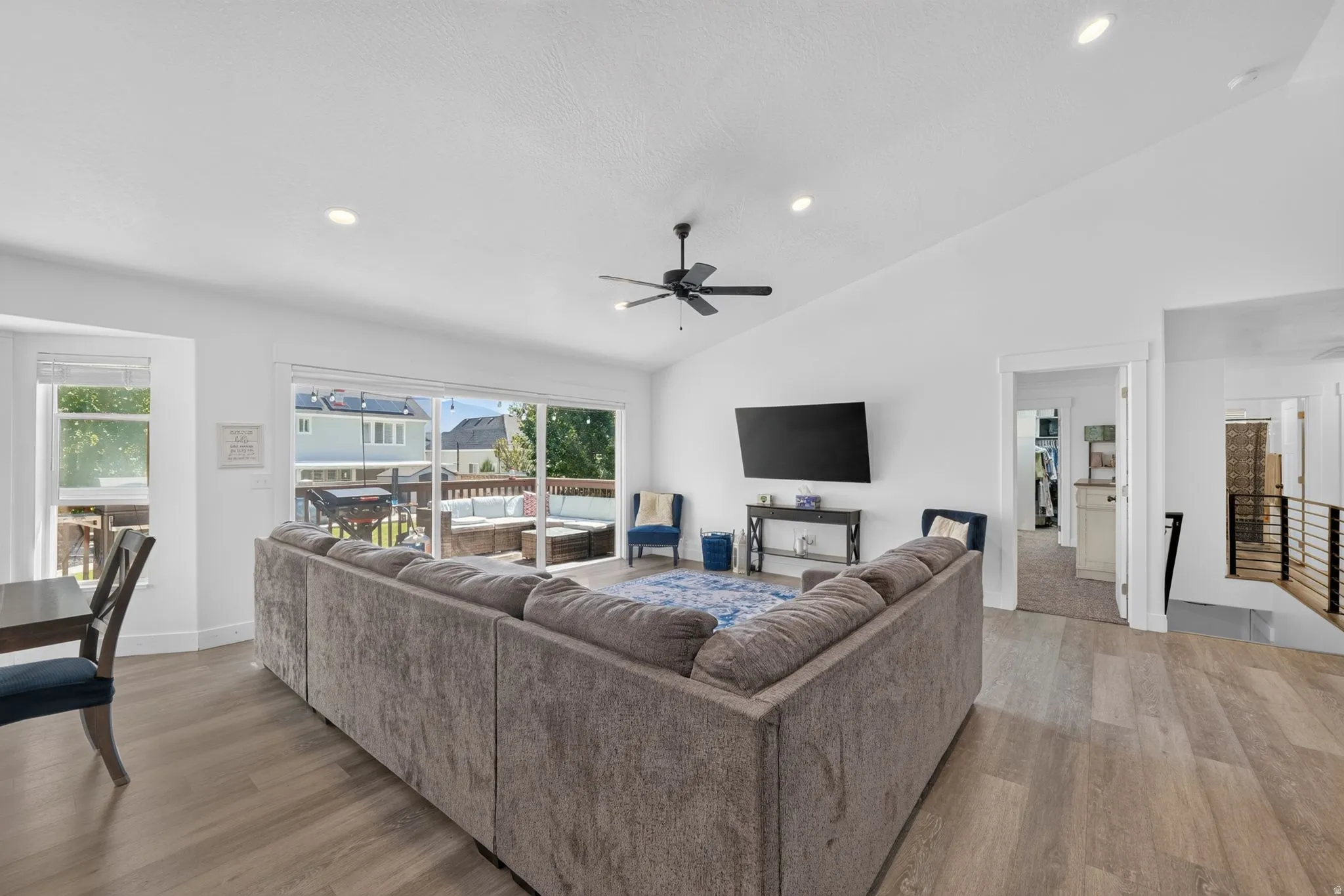 Vaulted ceilings, wood-finish flooring, recessed lighting, and a ceiling fan
