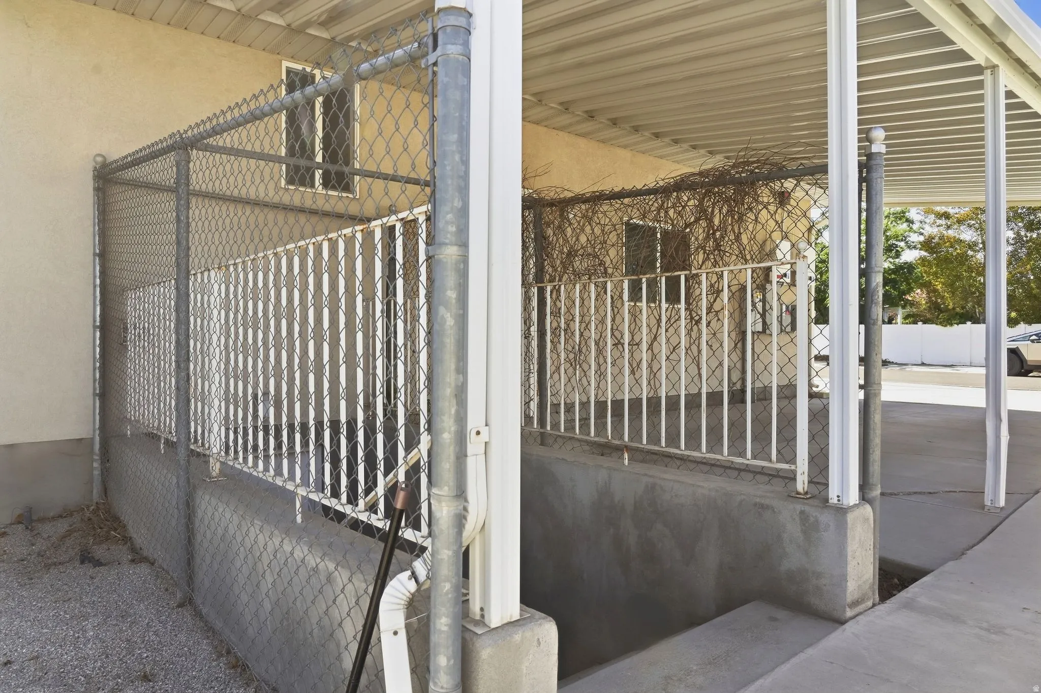Carport structure with corrugated metal roofing, supporting posts, and concrete pad