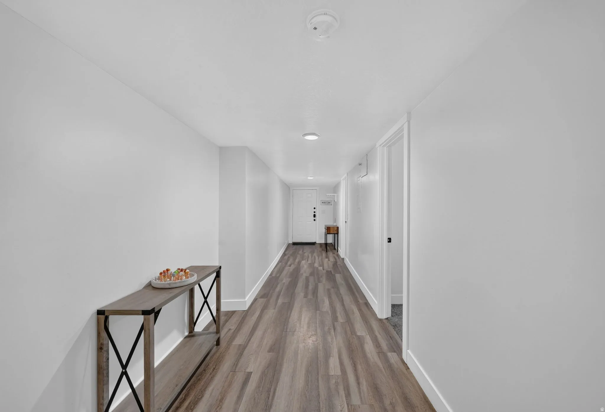 Long hallway featuring wood-finish flooring, white walls, and recessed lighting