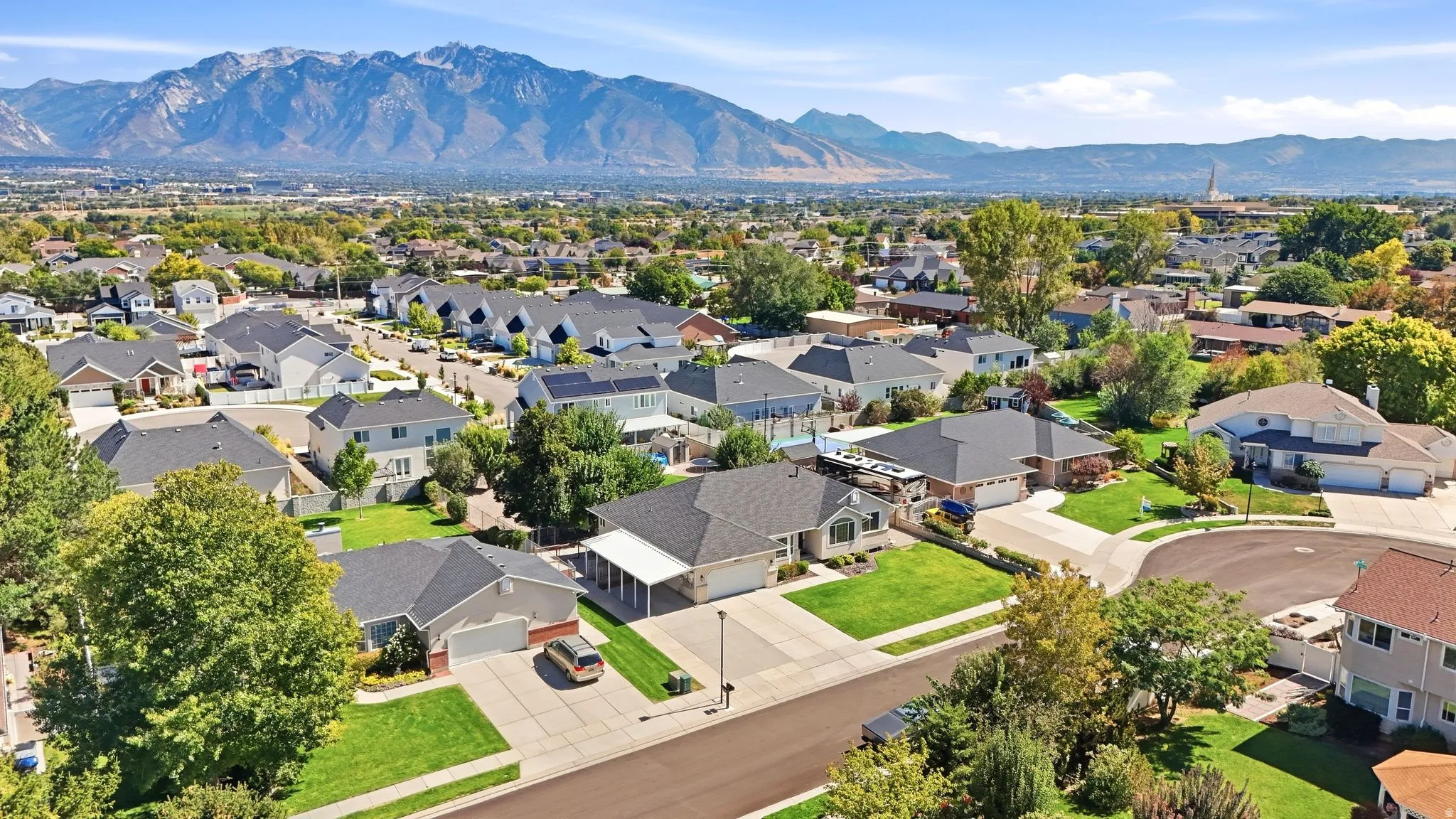 Residential neighborhood with a mountain backdrop, mature landscaping, and varied architectural styles