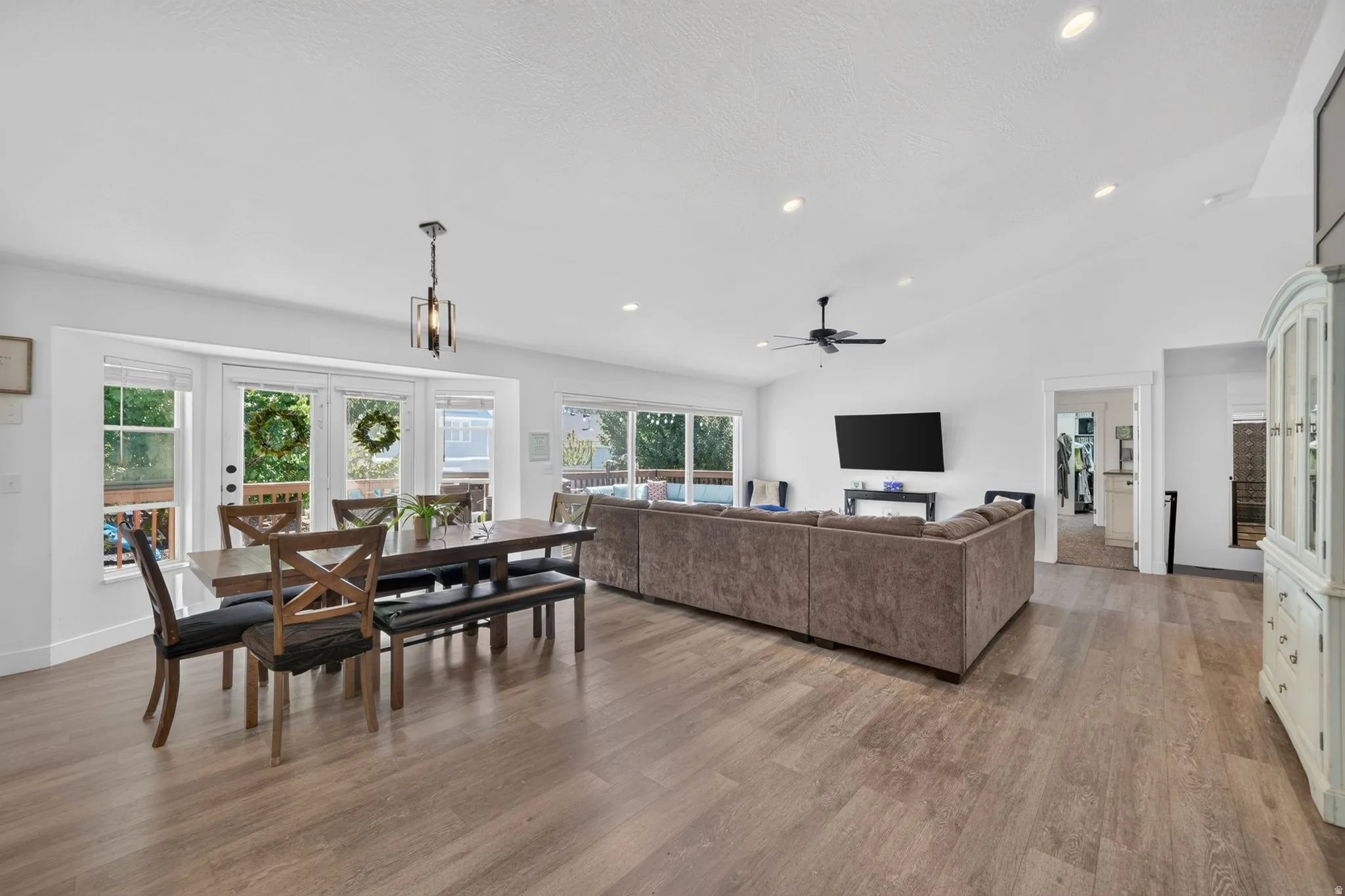 Open-concept living space featuring wood-finish flooring, recessed lighting, and vaulted ceilings