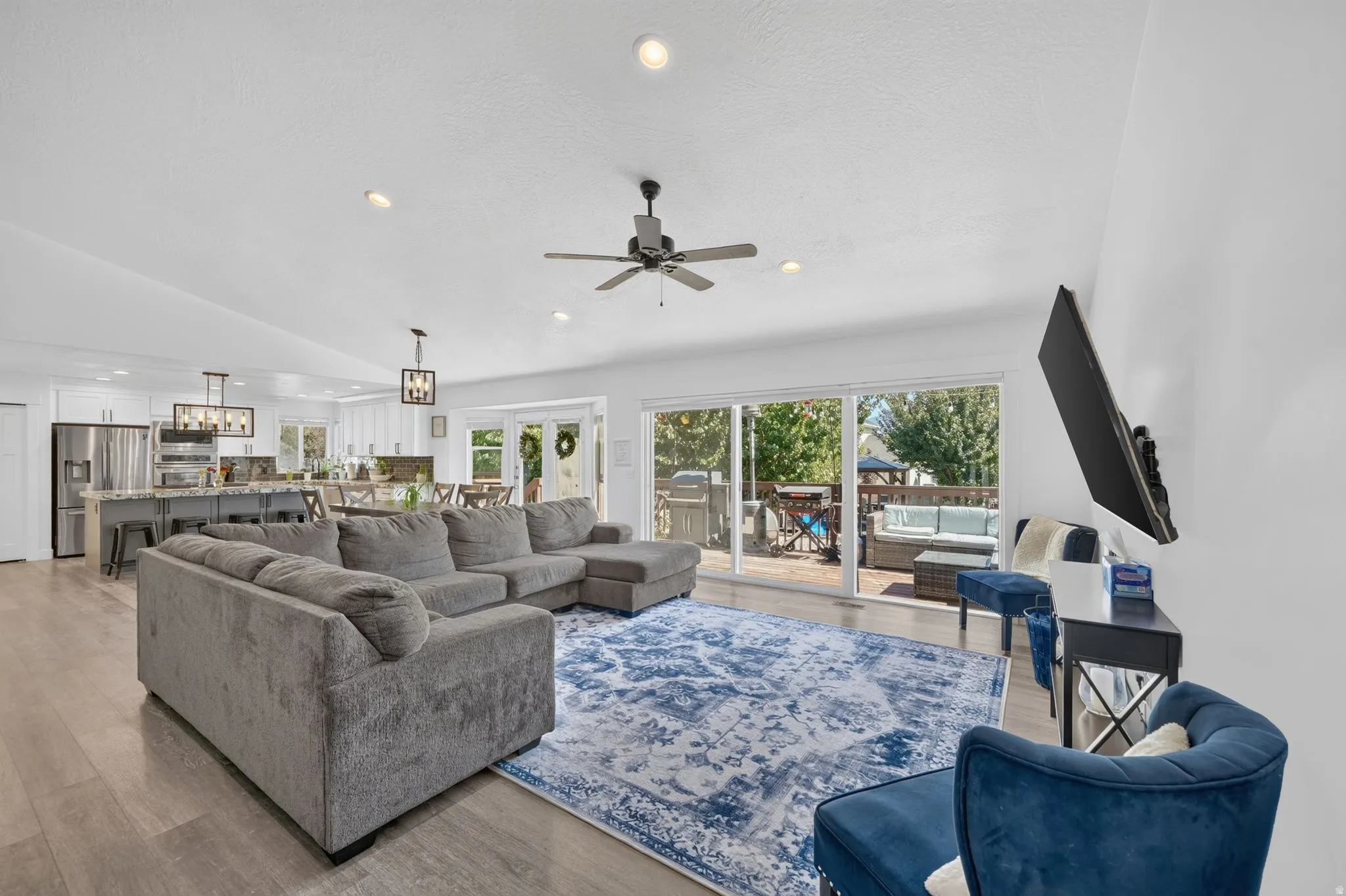 Open-concept living area with wood-finish flooring, recessed lighting, and a ceiling fan