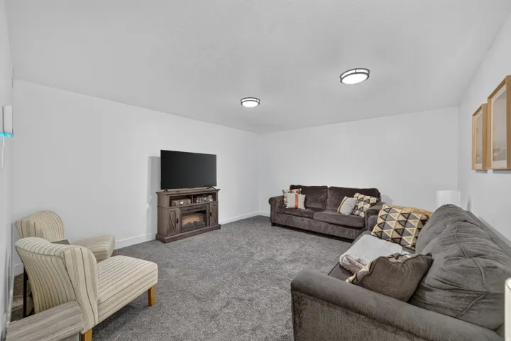 Plush carpet flooring, neutral white wall finishes, and integrated ceiling lighting