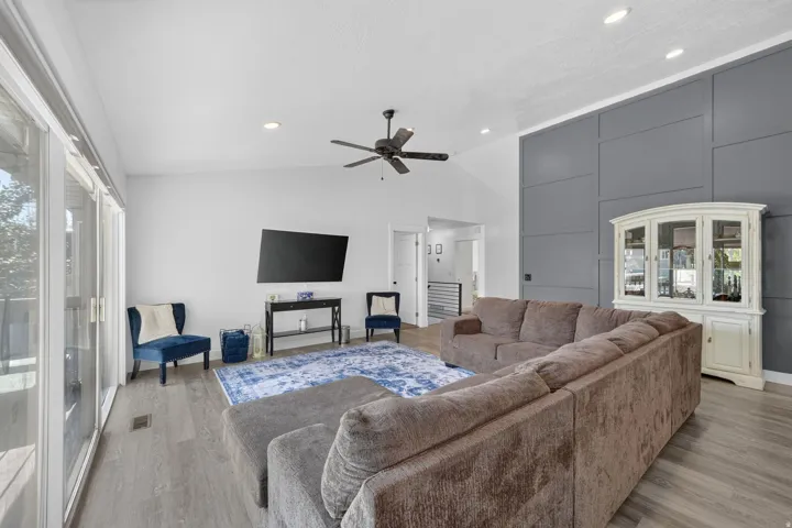 Vaulted ceiling with a ceiling fan, recessed lighting, and wood-finish flooring