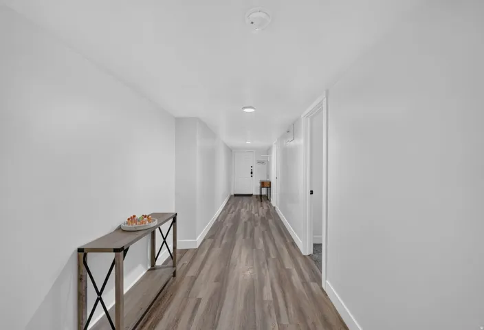 Long hallway featuring wood-finish flooring, white walls, and recessed lighting