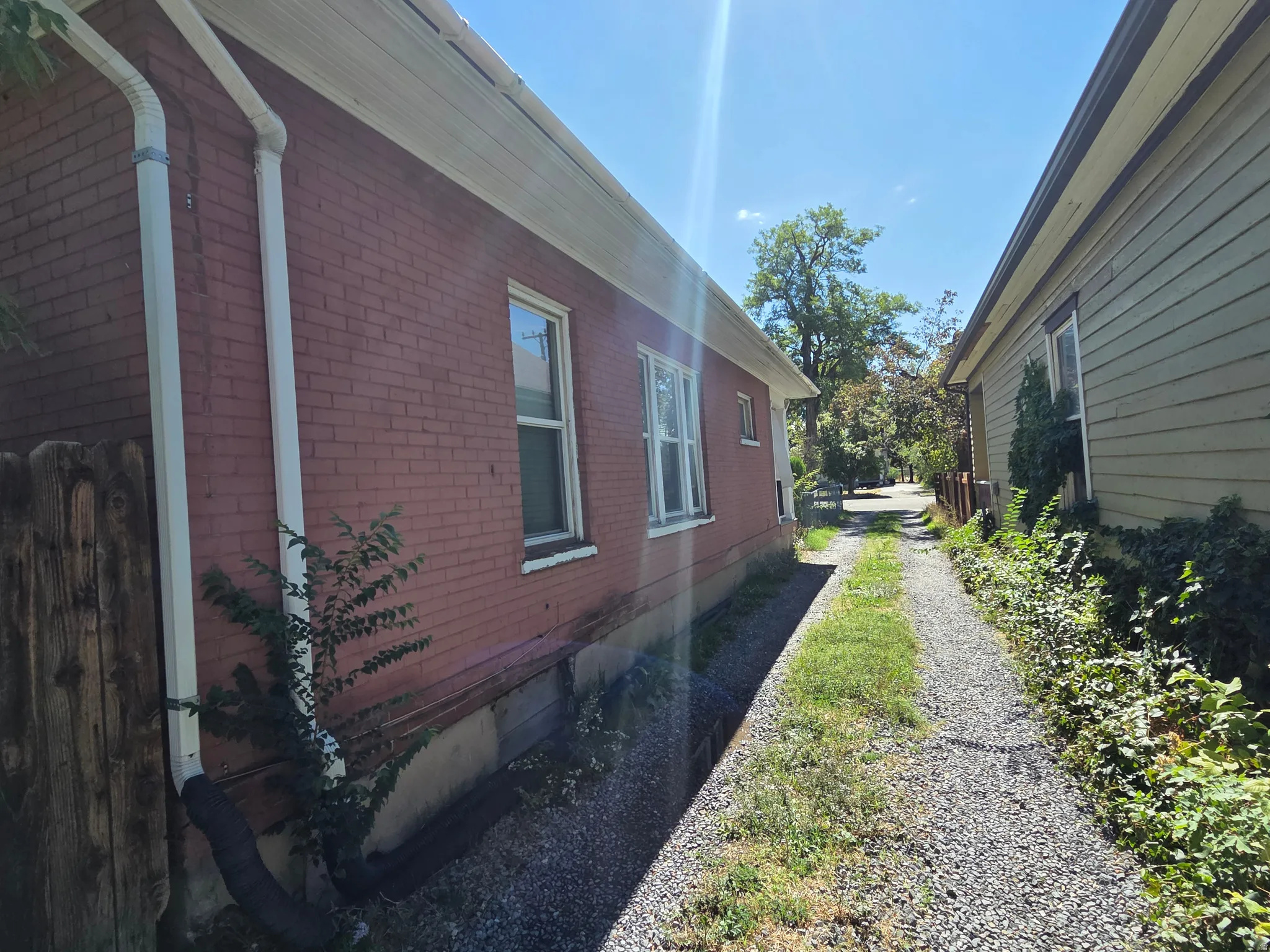 Brick exterior with white downspouts and a gravel path