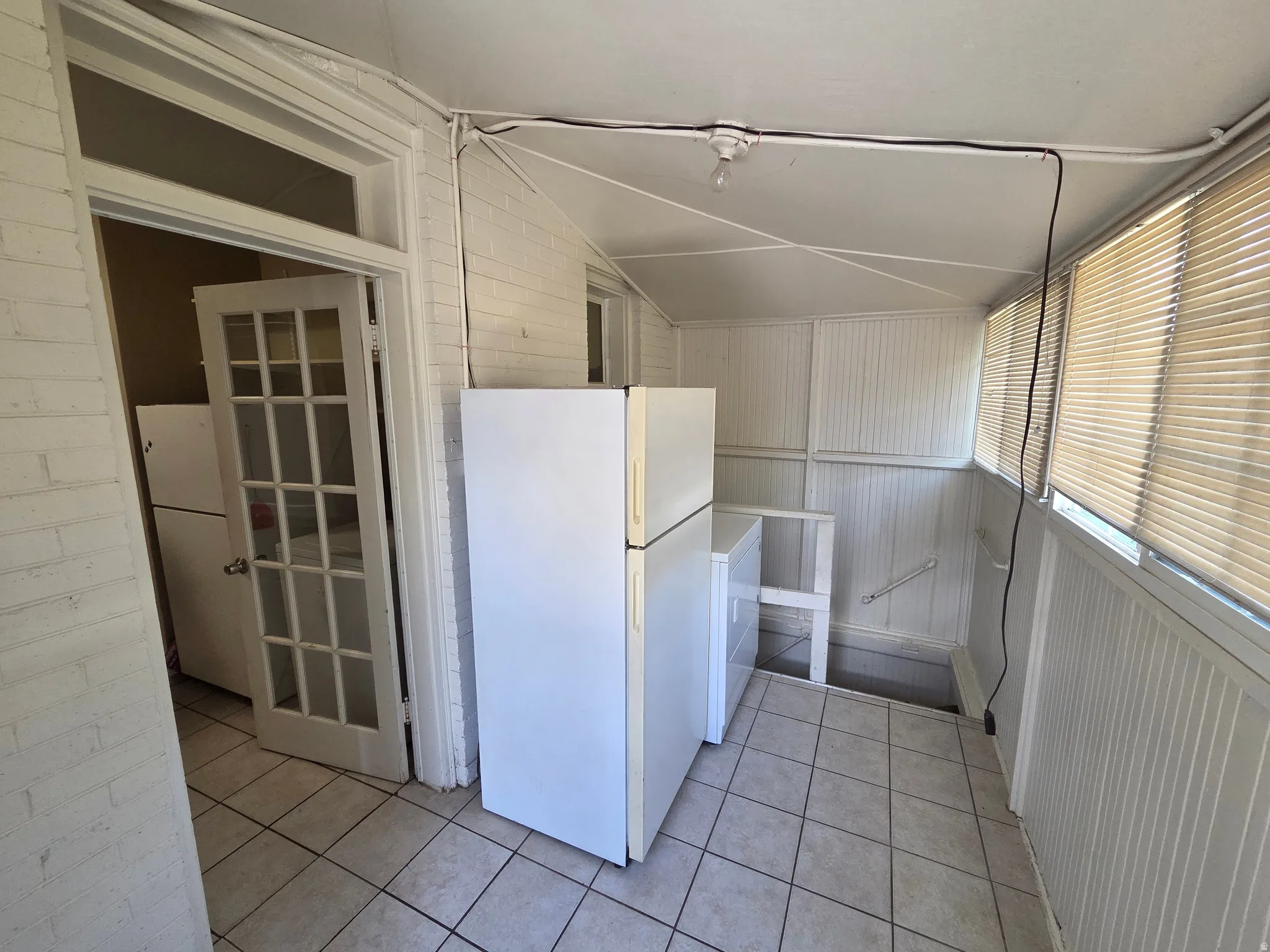 Tiled flooring with white brick and beadboard walls