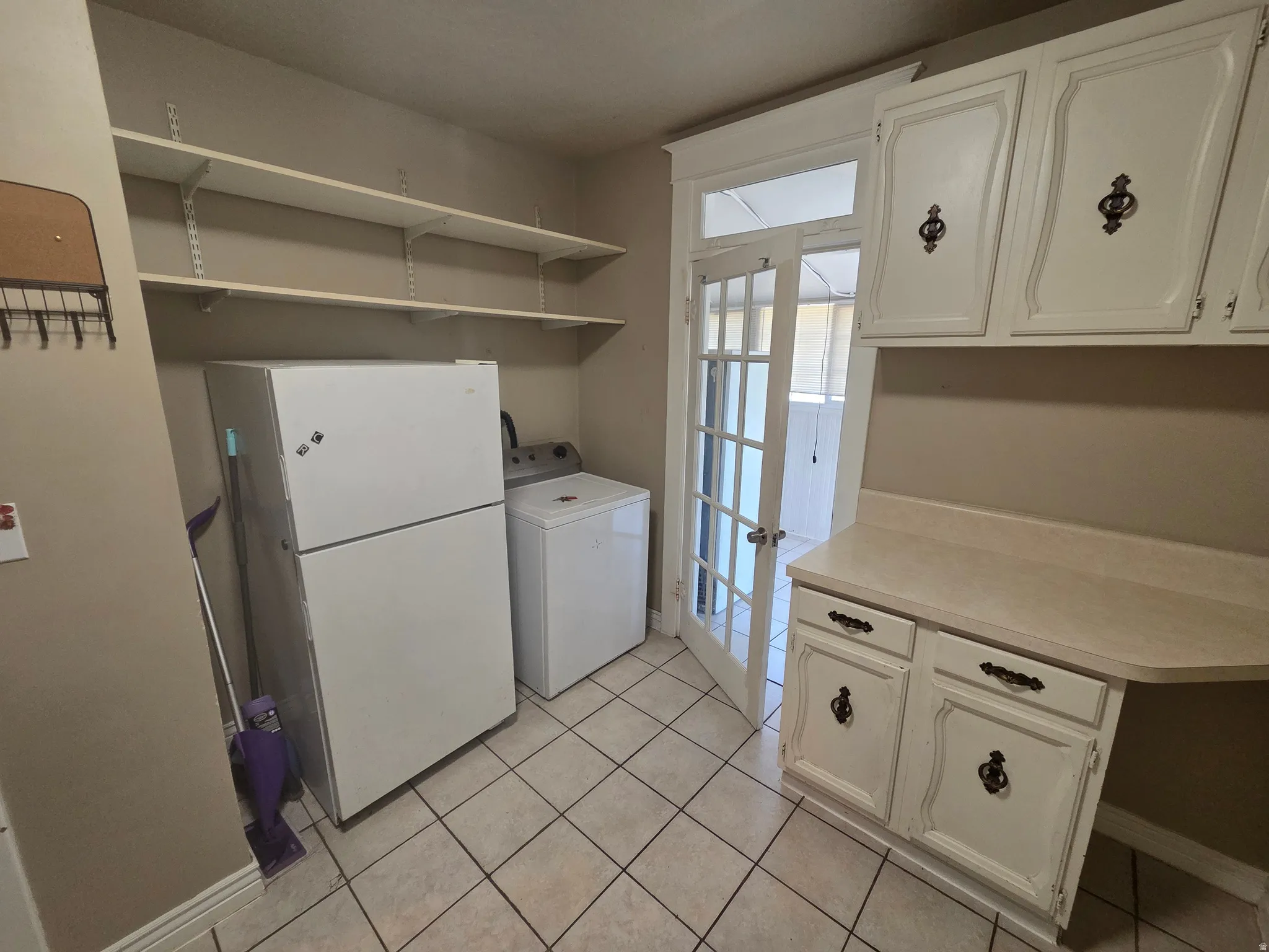White wood-finish cabinetry, tile flooring, built-in shelving, and a French door with glass panels