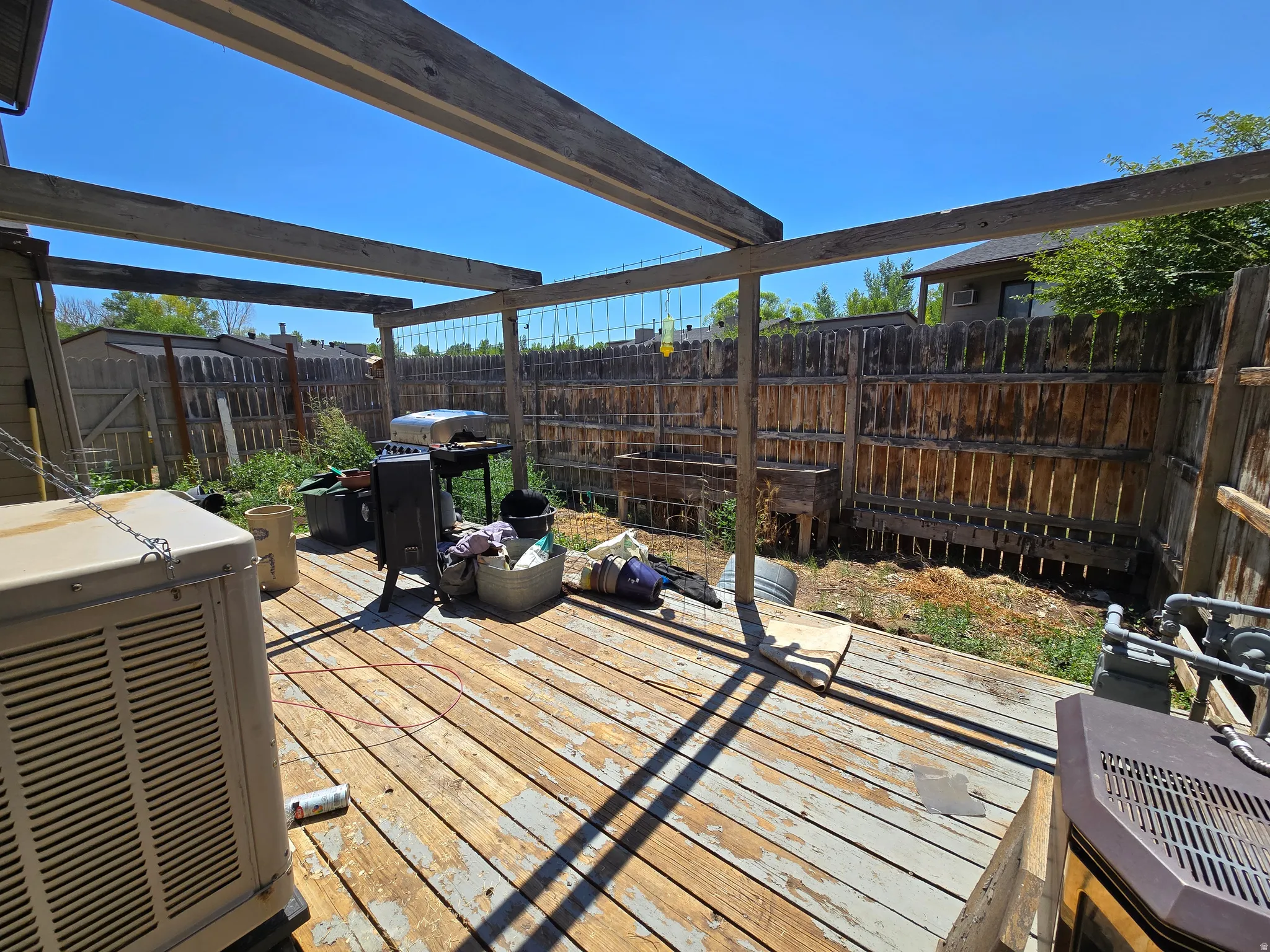 Wood-finish deck with open pergola framework and privacy fencing