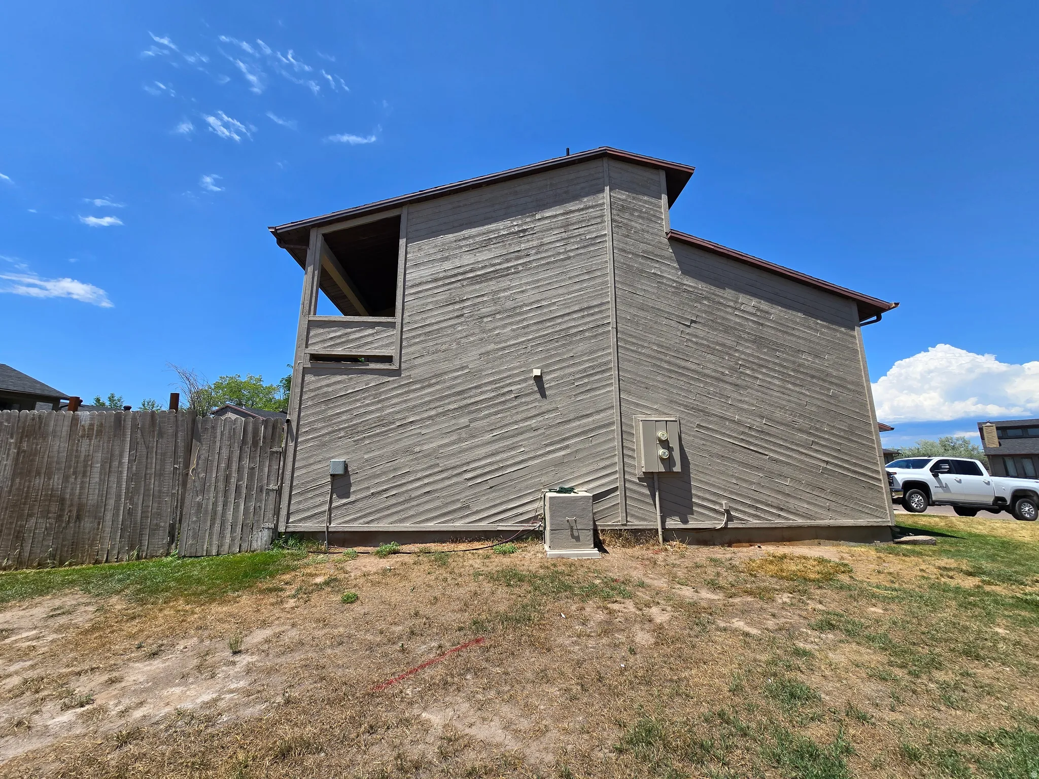 Exterior wall featuring horizontal wood-finish siding, a covered upper-level patio, and a privacy fence